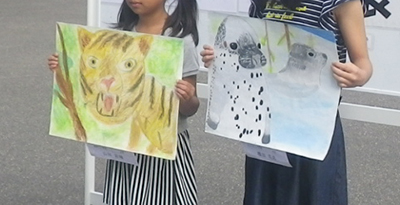 写真：描いた絵を持った2人の女子児童