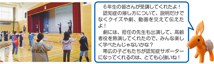 写真：子供たちとロバ隊長の説明「6年生の皆さんが受講してくれたよ！認知症の接し方について、説明だけでなくクイズや劇、動画を交えて伝えたよ。劇には、担任の先生も出演して、高齢者の役を熱演してくれたので、みんな楽しく学べたんじゃないかな？帯広の子どもたちが認知症サポーターになってくれるのは、とても心強いね！」