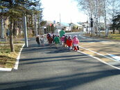 幅4mほどの広い歩道を園児たちが歩いている写真。